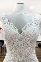 Robe de mariée sirène longue en dentelle, décolleté cœur et dos nu, ornée d'appliqués de dentelle.
