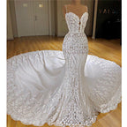 Robe de mariée sirène longue à fines bretelles spaghetti, ornée d'appliqués de dentelle et d'une traîne cathédrale.