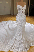 Robe de mariée sirène longue à fines bretelles spaghetti, ornée d'appliqués de dentelle et d'une traîne cathédrale.