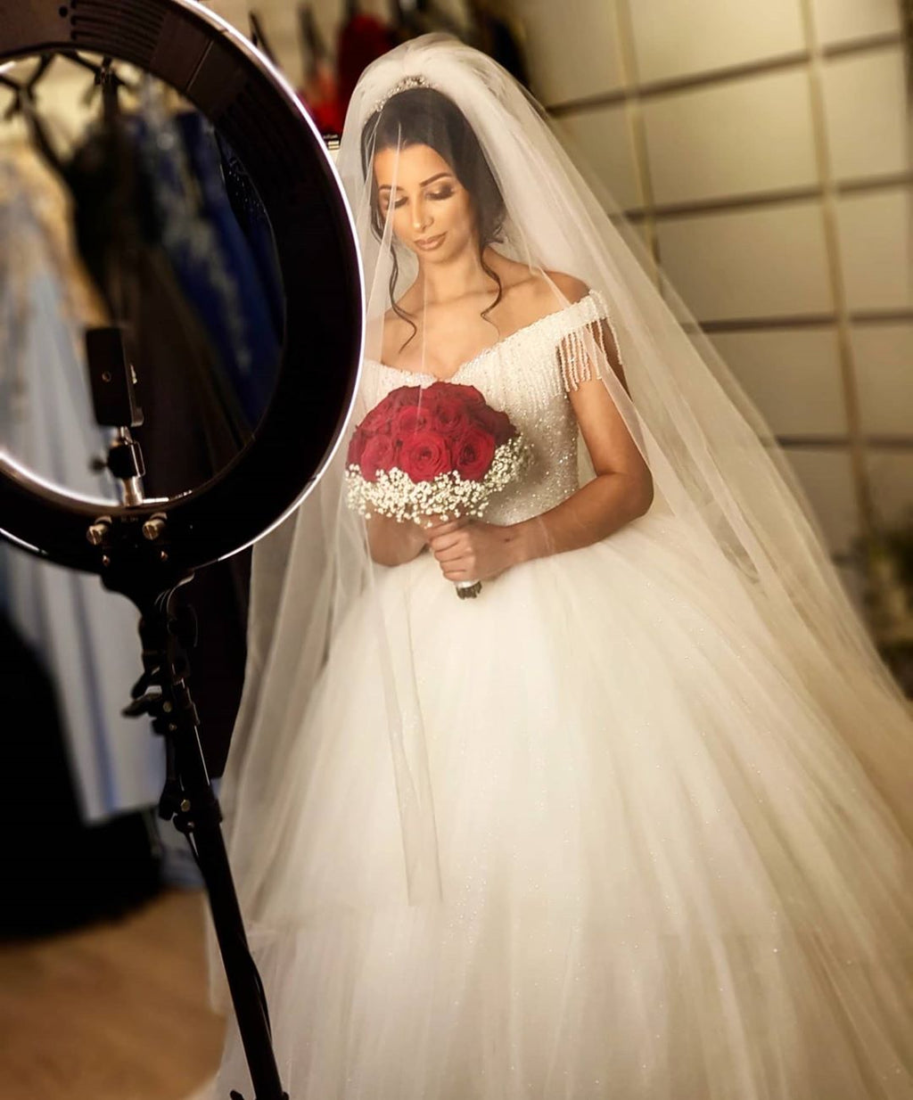 Robe de mariée longue princesse en tulle dos nu ornée de perles et de pompons, épaules dénudées, coupe princesse.
