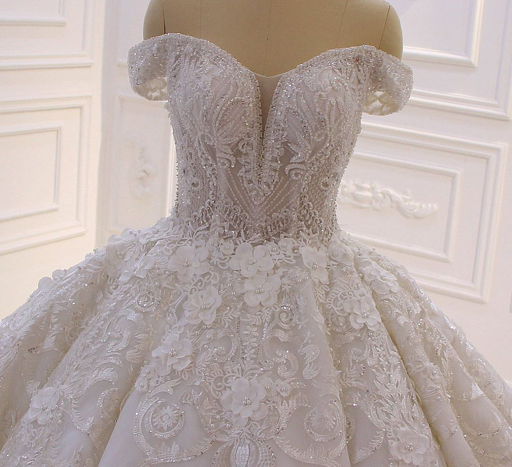 Robe de mariée longue princesse en tulle, décolleté cœur, épaules dénudées, dos nu, ornée d'appliques en dentelle et de volants.