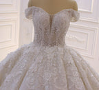 Robe de mariée longue princesse en tulle, décolleté cœur, épaules dénudées, dos nu, ornée d'appliques en dentelle et de volants.
