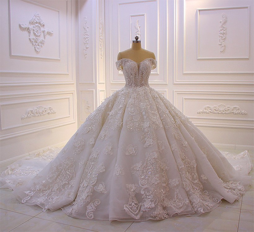 Robe de mariée longue princesse en tulle, décolleté cœur, épaules dénudées, dos nu, ornée d'appliques en dentelle et de volants.