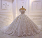 Robe de mariée longue princesse en tulle, décolleté cœur, épaules dénudées, dos nu, ornée d'appliques en dentelle et de volants.