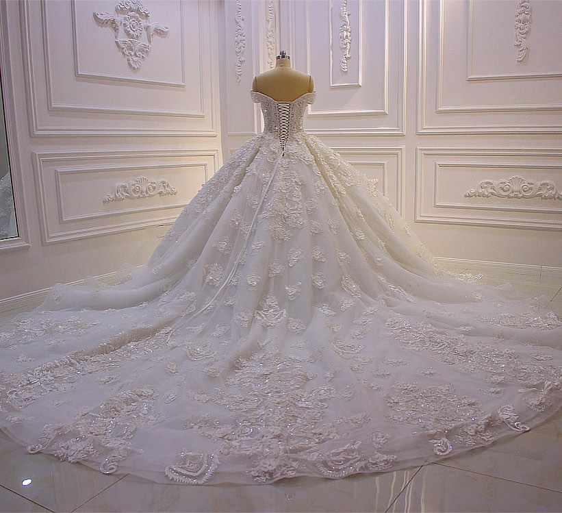 Robe de mariée longue princesse en tulle, décolleté cœur, épaules dénudées, dos nu, ornée d'appliques en dentelle et de volants.