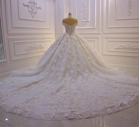 Vestido de novia largo de princesa con escote corazón, hombros descubiertos, espalda descubierta, apliques de encaje, volantes y tul.