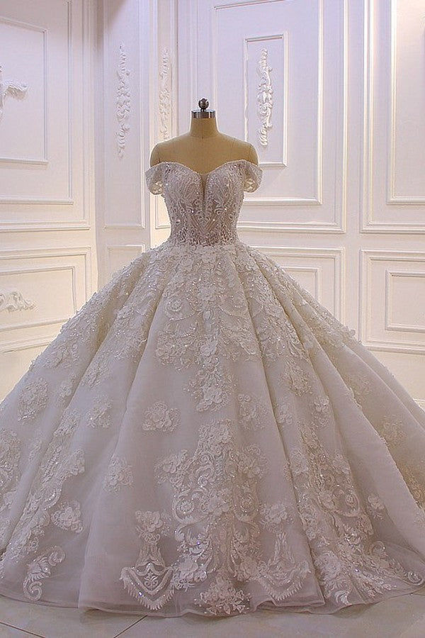 Robe de mariée longue princesse en tulle, décolleté cœur, épaules dénudées, dos nu, ornée d'appliques en dentelle et de volants.