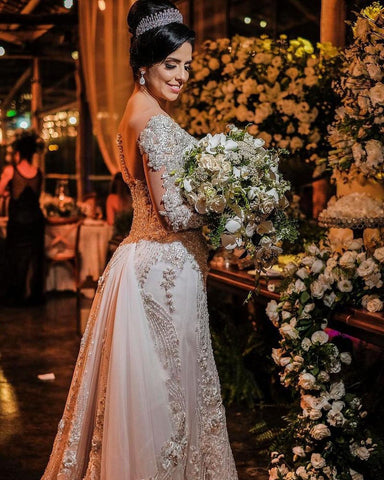 Vestido de novia de tul corte sirena, manga larga, hombros descubiertos, con apliques de encaje y mangas largas.