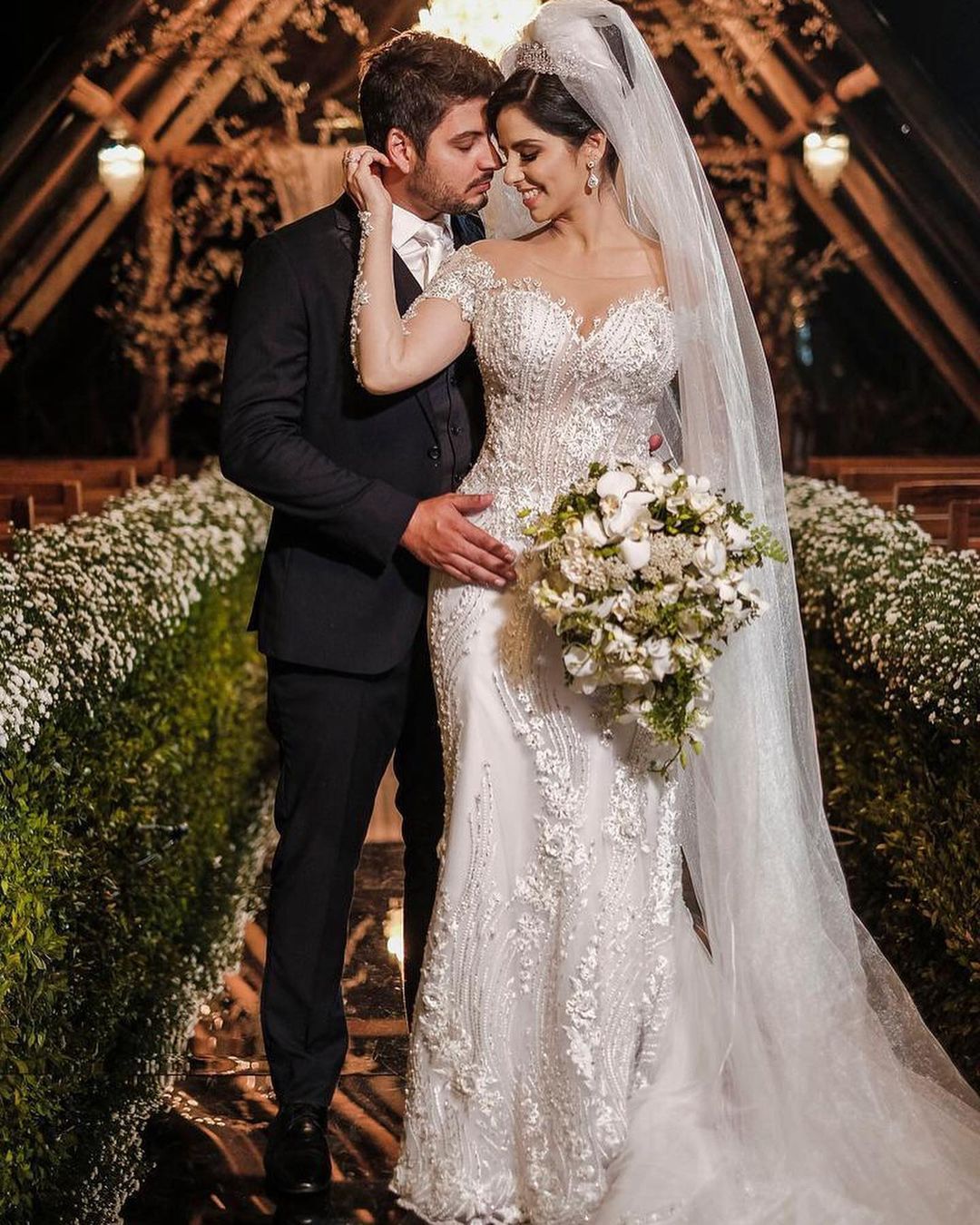 Vestido de novia de tul corte sirena, manga larga, hombros descubiertos, con apliques de encaje y mangas largas.