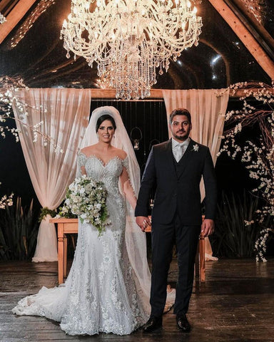 Vestido de novia de tul corte sirena, manga larga, hombros descubiertos, con apliques de encaje y mangas largas.