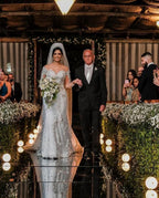 Vestido de novia de tul corte sirena, manga larga, hombros descubiertos, con apliques de encaje y mangas largas.