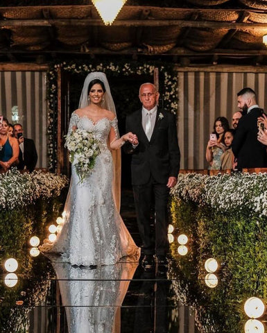 Vestido de novia de tul corte sirena, manga larga, hombros descubiertos, con apliques de encaje y mangas largas.