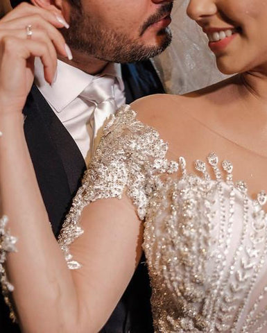 Vestido de novia de tul corte sirena, manga larga, hombros descubiertos, con apliques de encaje y mangas largas.