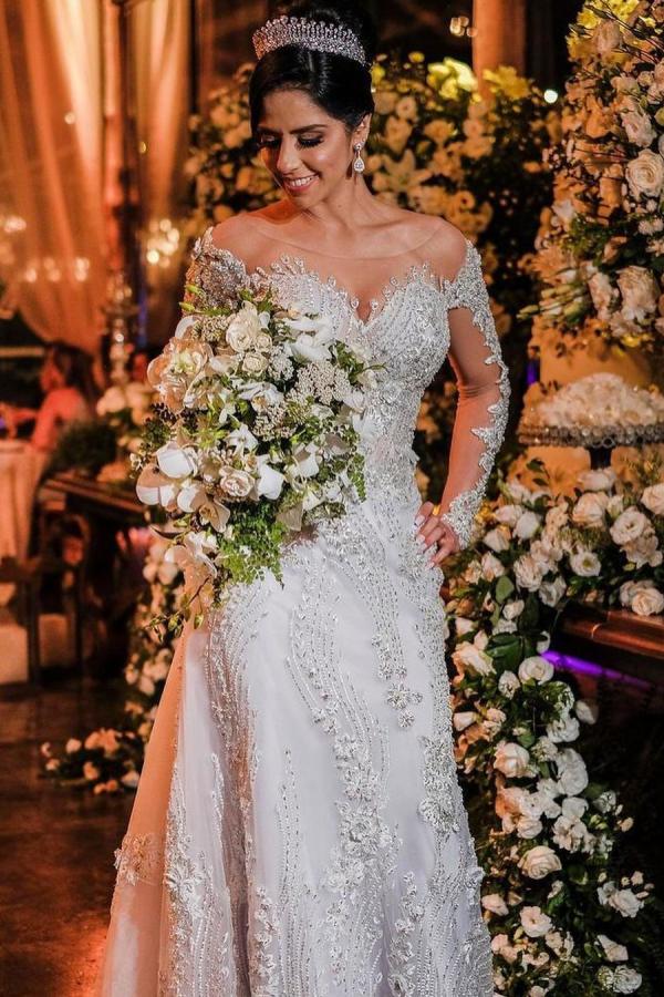 Vestido de novia de tul corte sirena, manga larga, hombros descubiertos, con apliques de encaje y mangas largas.