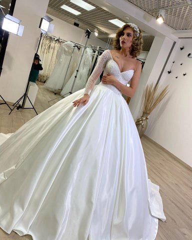Vestido de novia largo de satén con escote corazón, volantes y mangas, estilo princesa.