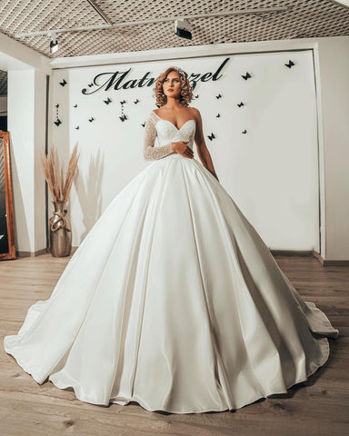 Vestido de novia largo de satén con escote corazón, volantes y mangas, estilo princesa.