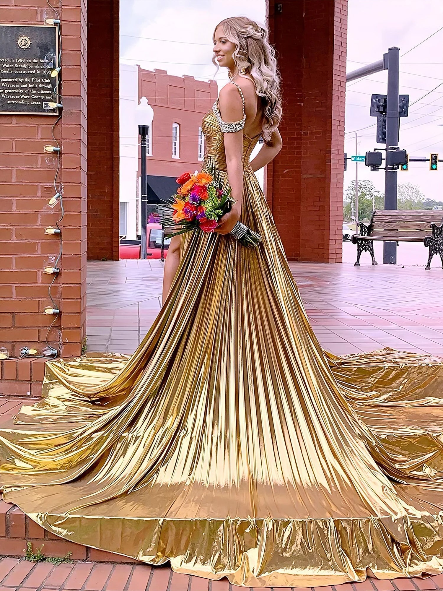 Lulu | Vestido largo de gala dorado con hombros descubiertos, corte en A y pliegues metálicos 