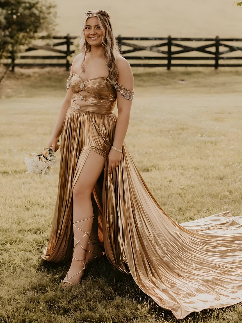 Lulu | Vestido largo de gala dorado con hombros descubiertos, corte en A y pliegues metálicos 