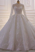 Lujoso vestido de novia de encaje con lentejuelas, corte línea A y cuello alto, con mangas largas.