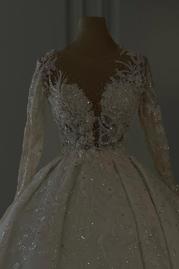 Vestido de novia largo de encaje color marfil, corte en A, escote en V, mangas largas y brillo, con lentejuelas.