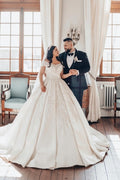 Luxueuse robe de mariée longue blanche en satin, coupe trapèze, épaules dénudées et dentelle.