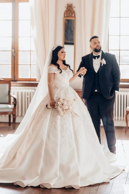 Luxueuse robe de mariée longue blanche en satin, coupe trapèze, épaules dénudées et dentelle.