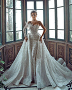 Luxueuse robe de mariée blanche longue asymétrique à une épaule, ornée de perles et de broderies, avec traîne.