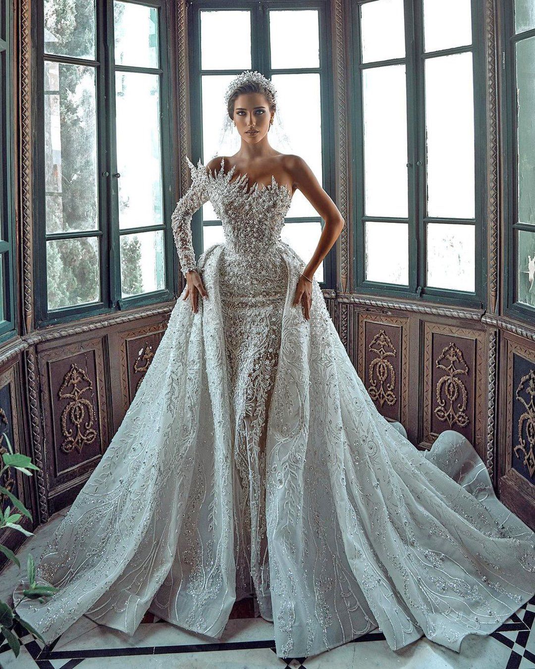 Luxueuse robe de mariée blanche longue asymétrique à une épaule, ornée de perles et de broderies, avec traîne.