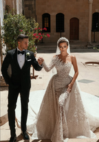 Luxueuse robe de mariée blanche longue asymétrique à une épaule, ornée de perles et de broderies, avec traîne.