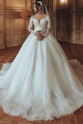 Robe de mariée luxueuse en tulle et dentelle blanche, longue, à col rond et manches longues.