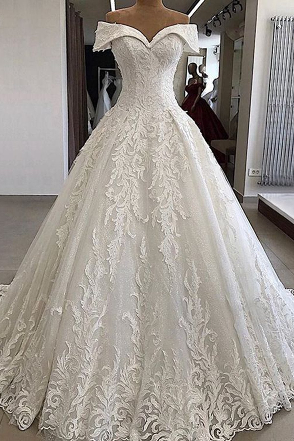 Robe de mariée longue de luxe en dentelle appliquée, épaules dénudées et coupe trapèze.