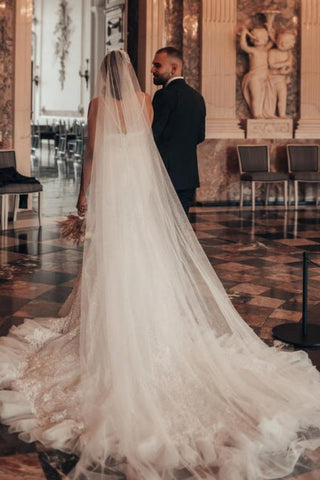Robe de mariée sirène longue de luxe à fines bretelles et paillettes, ornée de dentelle.