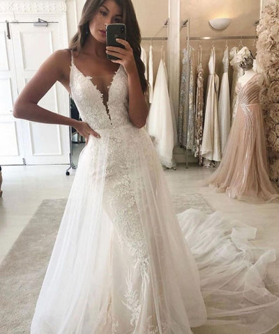 Vestido de novia estilo sirena con escote en V, tirantes y cola desmontable.