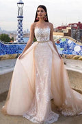 Robe de mariée sirène/trompette en dentelle, tulle et satin, bretelles classiques, transparente, col rond et traîne chapelle, bretelles régulières. 