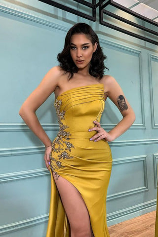 Vestido de noche moderno estilo sirena con apliques, abertura y sin tirantes.