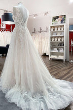 Robe de mariée en tulle, coupe trapèze, dos nu et décolleté en V, ornée d'appliqués de dentelle. Sage et élégante.