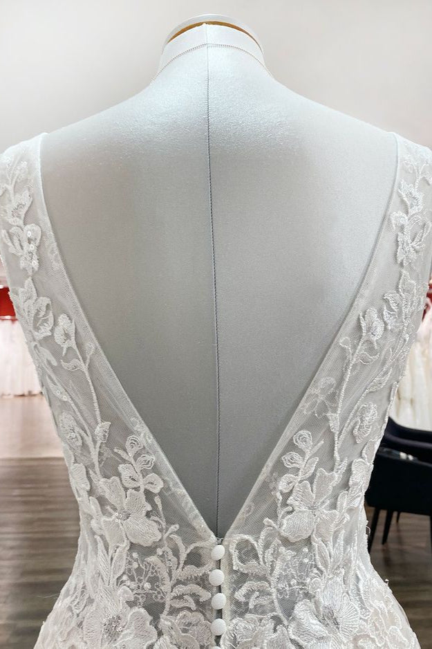 Robe de mariée en tulle, coupe trapèze, dos nu et décolleté en V, ornée d'appliqués de dentelle. Sage et élégante.