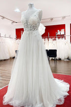 Robe de mariée sobre, longue, trapèze, col en V, en tulle à volants, dos nu et dentelle.