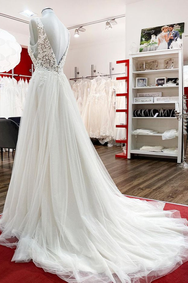 Robe de mariée sobre, longue, trapèze, col en V, en tulle à volants, dos nu et dentelle.