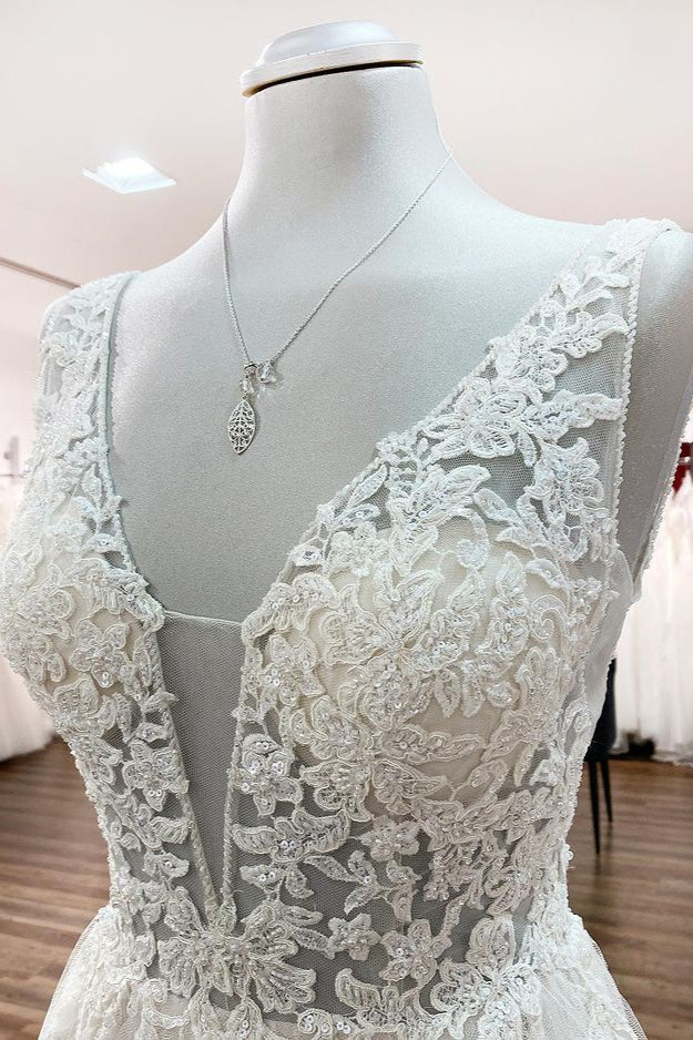 Robe de mariée sobre, longue, trapèze, col en V, en tulle à volants, dos nu et dentelle.