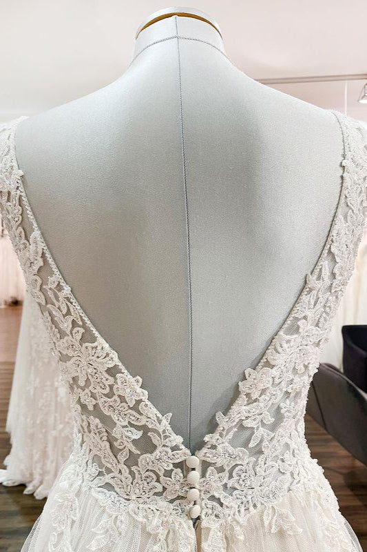 Robe de mariée sobre, longue, trapèze, col en V, en tulle à volants, dos nu et dentelle.