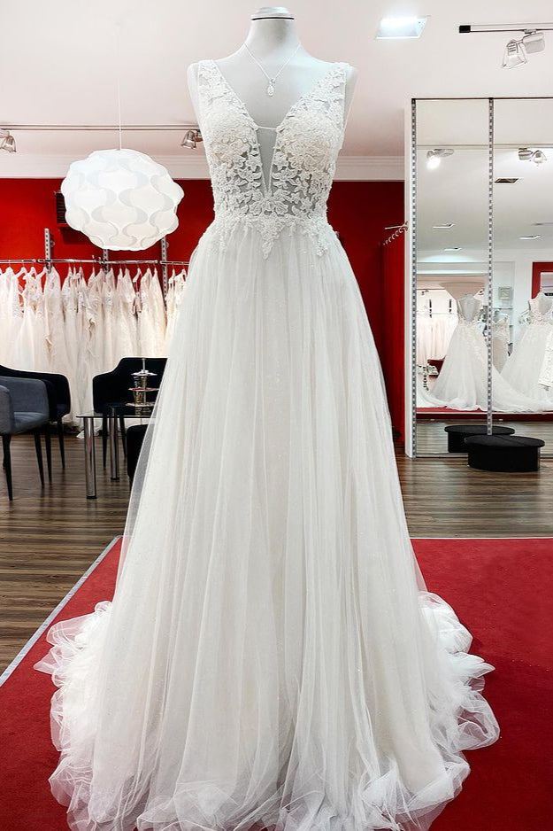 Robe de mariée sobre, longue, trapèze, col en V, en tulle à volants, dos nu et dentelle.
