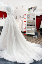 Robe de mariée princesse longue et sobre en tulle à fines bretelles et col en V, ornée de dentelle.