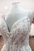 Robe de mariée princesse longue et sobre en tulle à fines bretelles et col en V, ornée de dentelle.