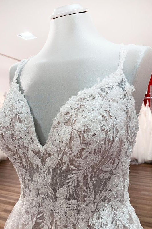 Robe de mariée princesse longue et sobre en tulle à fines bretelles et col en V, ornée de dentelle.