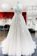 Robe de mariée princesse longue et sobre en tulle à fines bretelles et col en V, ornée de dentelle.