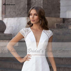 Vestido de novia Abiti Donna Modest Bridal corte A, verano 2025. Sencillo, con escote en V, espalda descubierta, ideal para bodas en la playa. Cola larga.