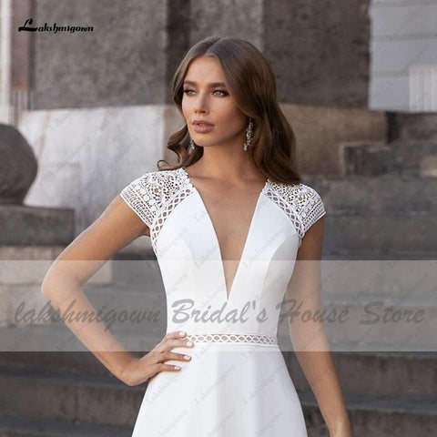 Vestido de novia Abiti Donna Modest Bridal corte A, verano 2025. Sencillo, con escote en V, espalda descubierta, ideal para bodas en la playa. Cola larga.