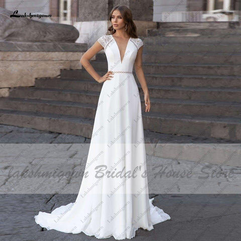 Vestido de novia Abiti Donna Modest Bridal corte A, verano 2025. Sencillo, con escote en V, espalda descubierta, ideal para bodas en la playa. Cola larga.
