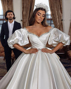 Robe de mariée princesse longue ivoire, coupe trapèze, col en V, ornée de bijoux et manches longues